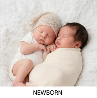 Two newborn babies in cozy Aatiyas Fashion cotton apparel lying on a soft white blanket