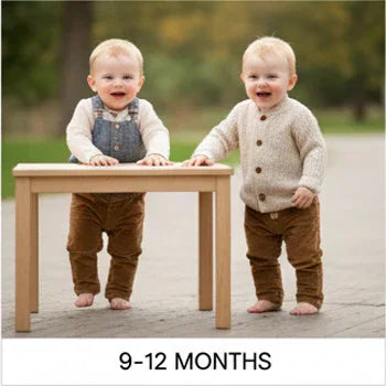 Two smiling babies in cozy Aatiyas Fashion outfits standing by a small table outdoors, 9-12 months