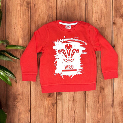 Red children's sweatshirt with WRU logo, wood background, Aatiyas Fashion kids apparel