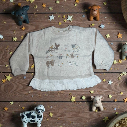 Aatiyas Fashion organic cotton girls' long sleeve top with farm animal print, lace trim, and toy animals on a wooden background.